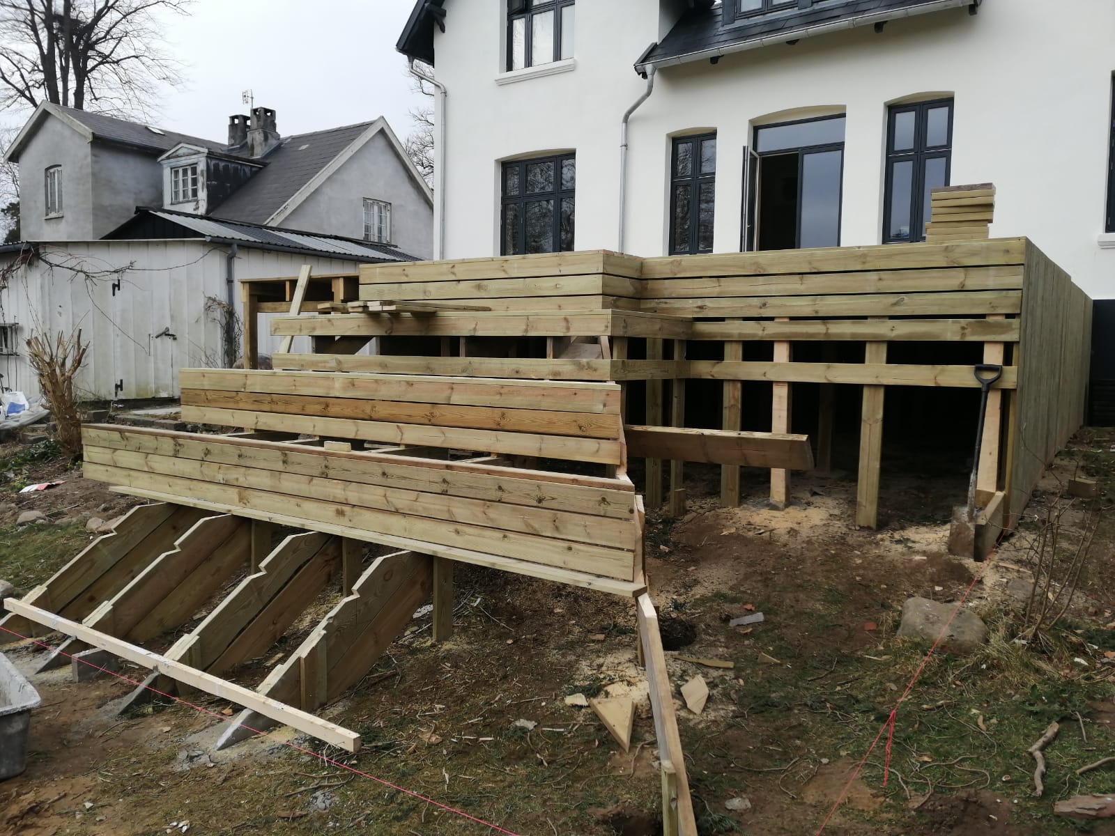 Stor terrasse og trappe i træ under opførelse ved hvid villa
